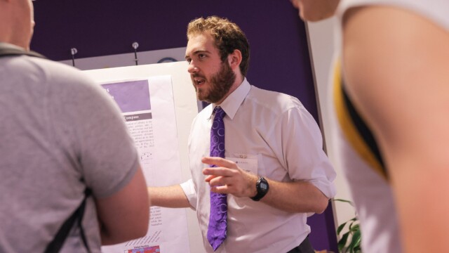 Michael Peeler '24 discusses his presentation with visitors during Family Weekend.