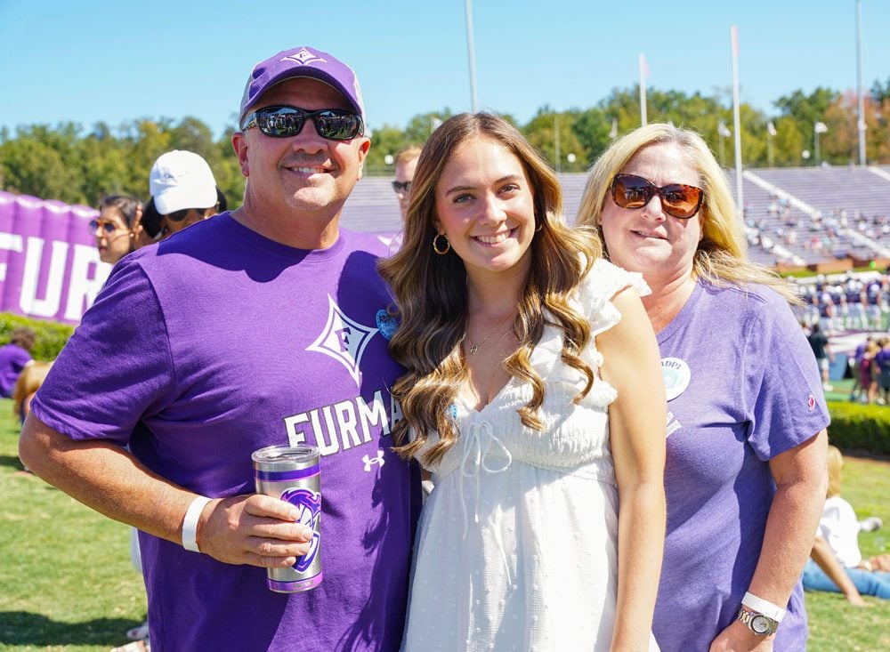 Student and her parents at a Furman football game