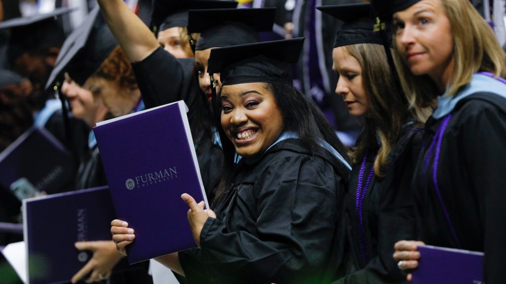 Student holding her diploma and grinning