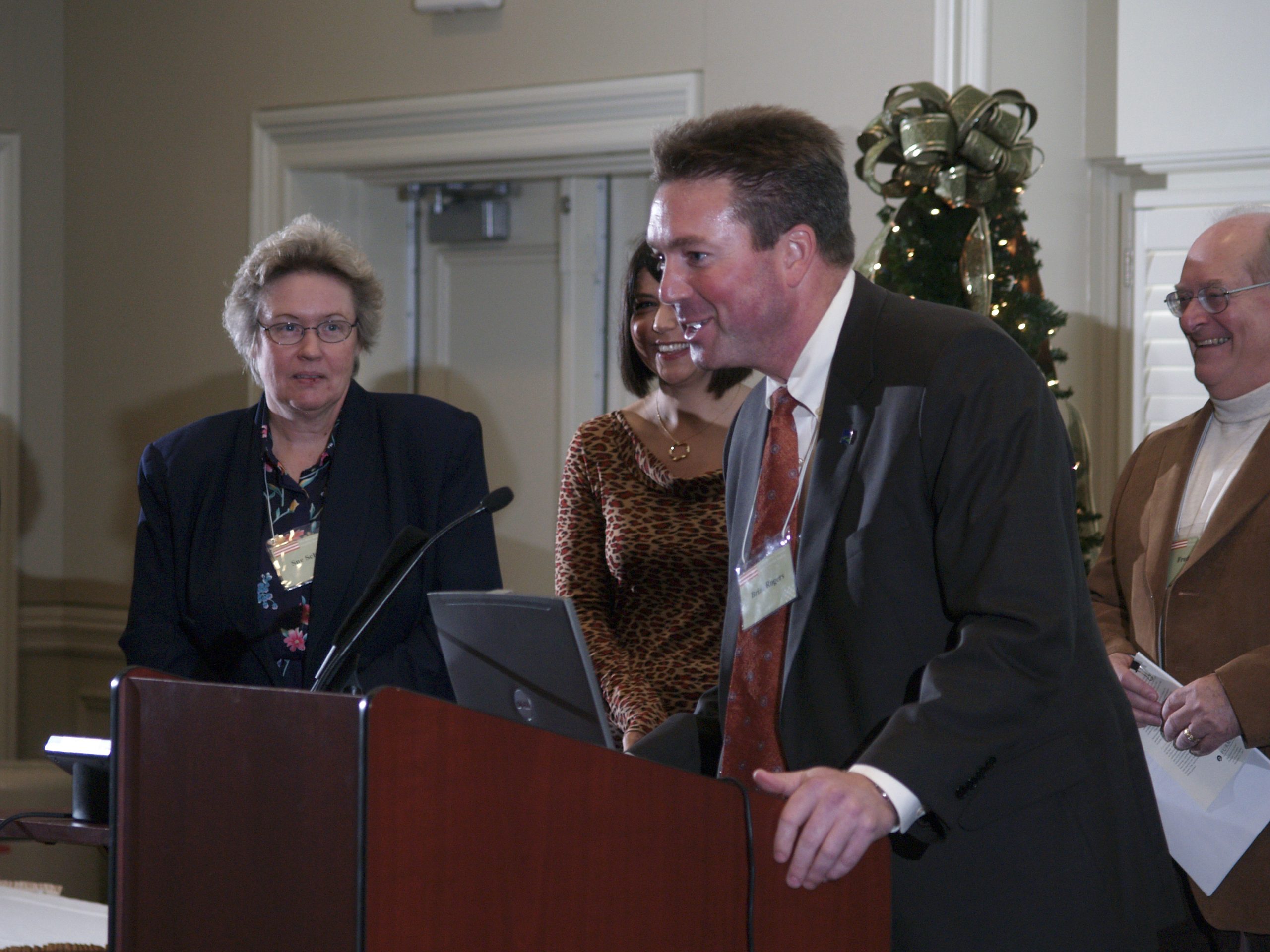 (l-r) Sue Schneider, Phyllis Martin (guest), Brian Rogers presenting, and Fred Baus
