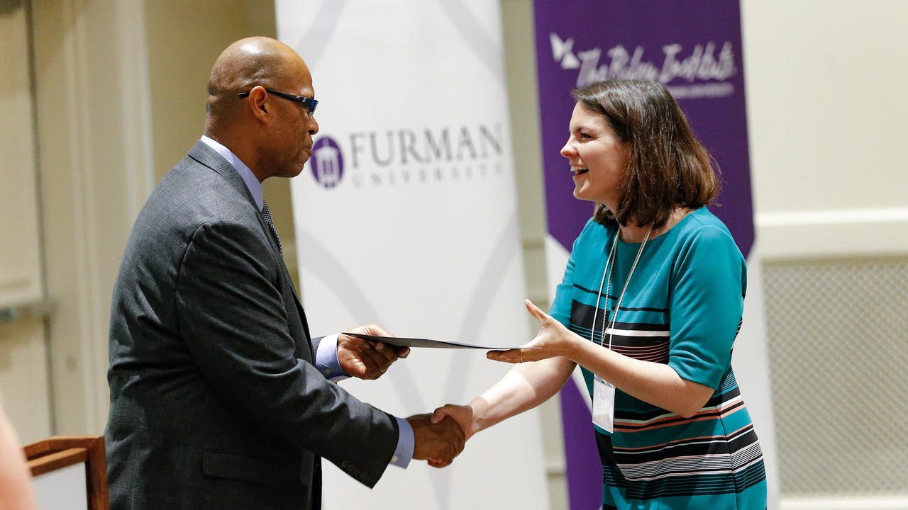 Juan John shakes hands with a DLI graduate and awards her a certificate