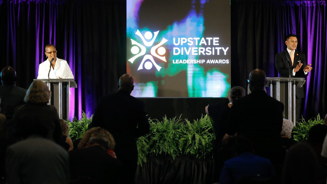 Two speakers stand at podiums at Upstate Diversity Leadership Awards