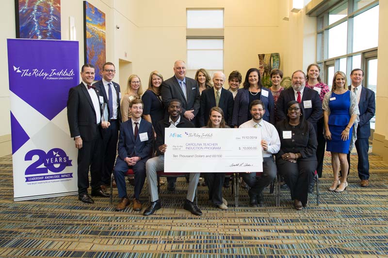 Award winner Carolina Teacher Induction Program. Row 1 seated (l-r): Chris Scudder, Mackie Wilson, Shannon Rowe, Michael Medlin and Tamara Turner; Row 2 (l-r): Jon Pedersen, Thomas Hodges, Marie McGehee, Nicole Skeen, Jamie Hennessy, Erin Eigenbrot, Dick Riley, Sherry Whatley, Cindy Van Buren, Lisa Davis, Morgan Lee, Angela Adams, Cathy Stevens and Don Gordon