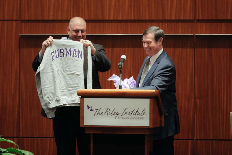 Don Gordon presenting a Furman sweatshirt to Jamie Hennessy, Vice President of Pre-Sale and Aflac Group Operations