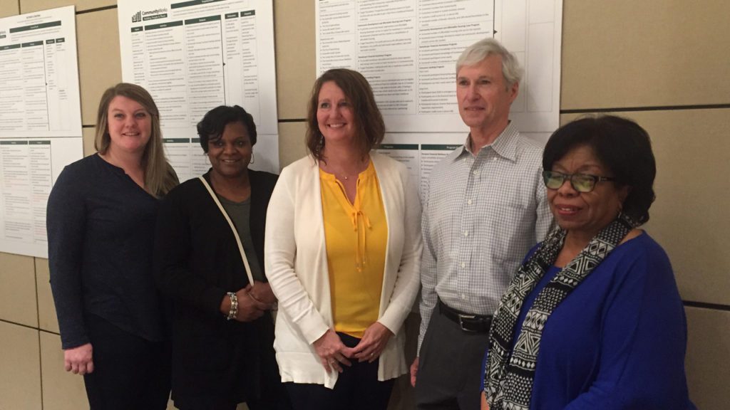 A group of professionals stand in front of theory of change documentation