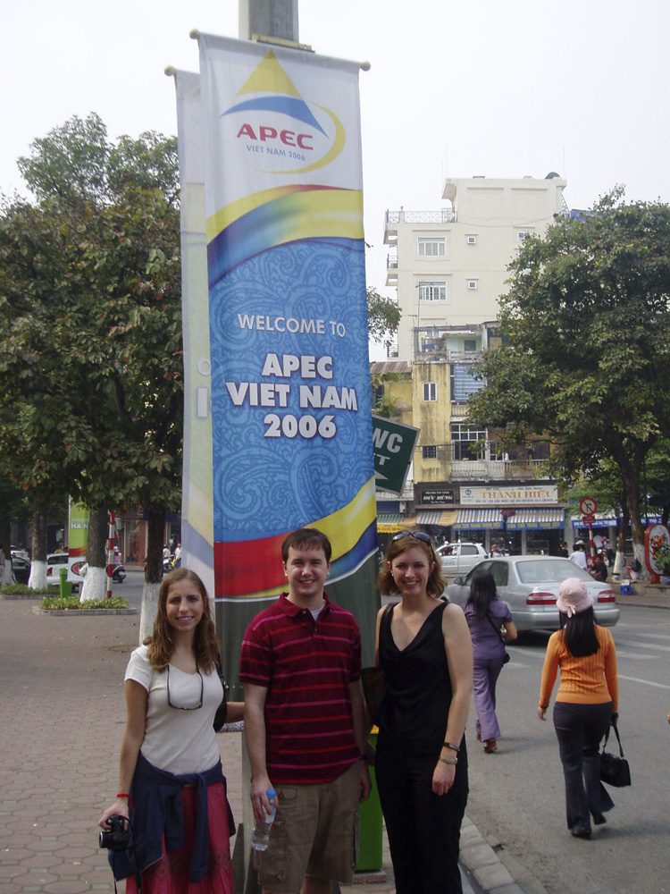 (l-r) Kristen Capogrossi, Daniella Fergusson, and Webb McArthur in front of the many APEC signs in Hanoi