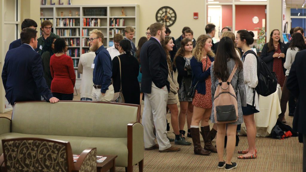 Students congregate for conversations inside a building at Furman