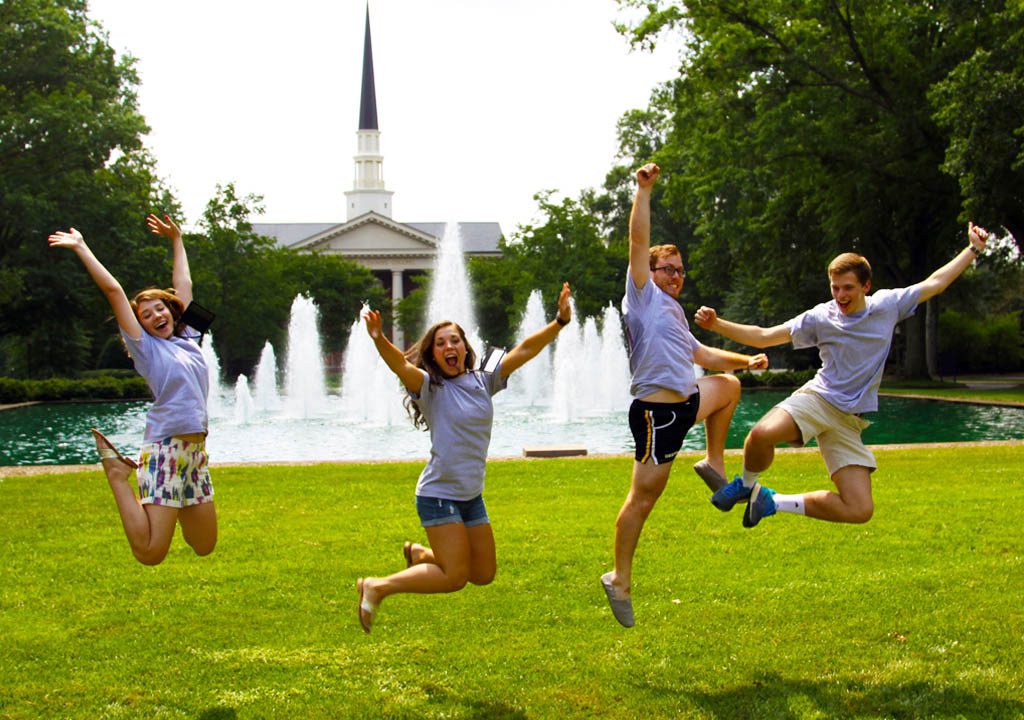 Students jump in front of a fountain on campus
