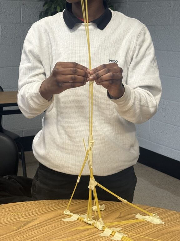 Hands of student doing a project with dry noodles
