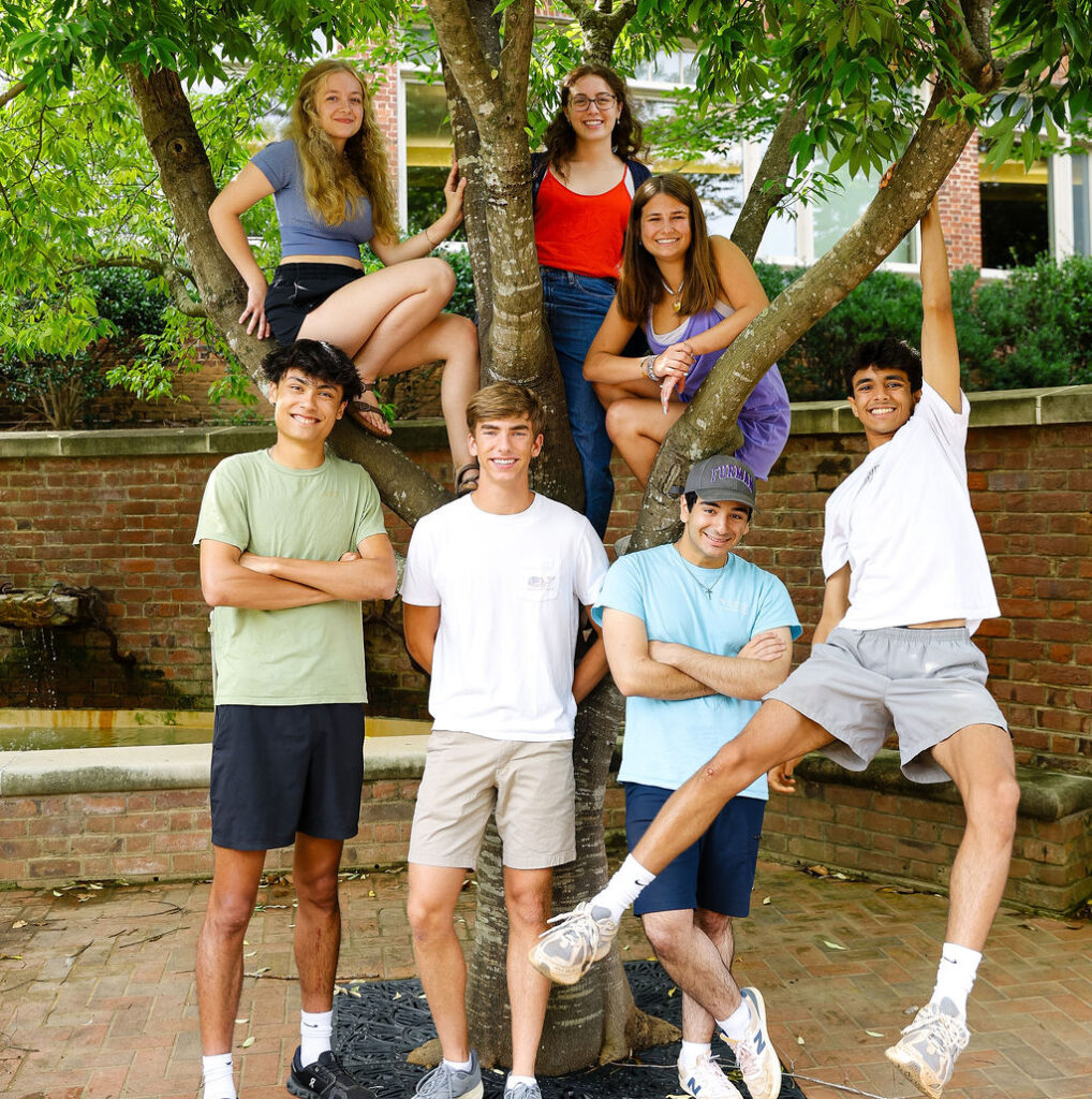 Group of students smiling, posing by a tree