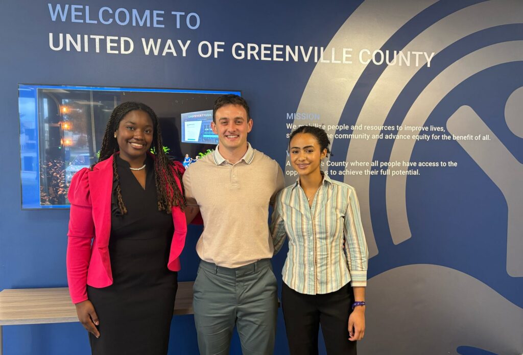 Three interns standing in front of a wall reaing "United Way of Greenville"