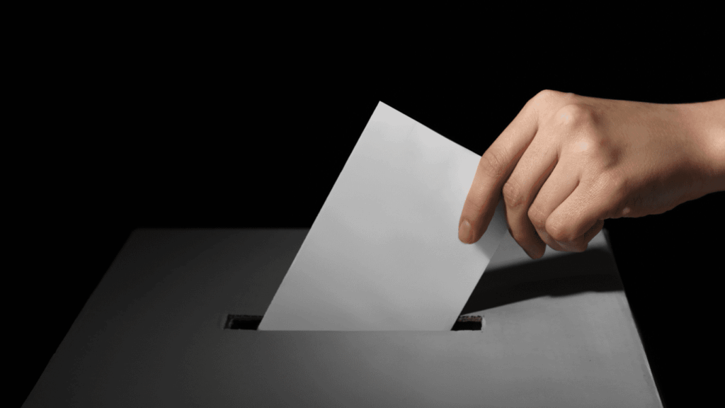 Hand putting an envelope in the ballot box
