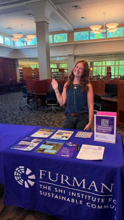 Student waving at informational table