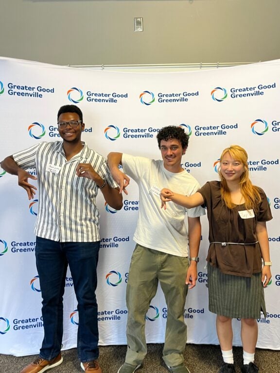 Three students forming letters FORR with their fingers