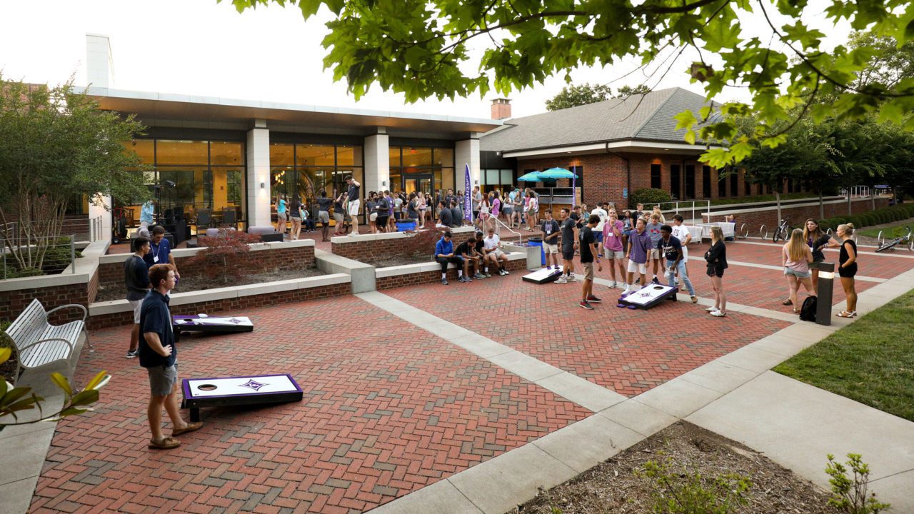 Students playing corn hole outside Trone