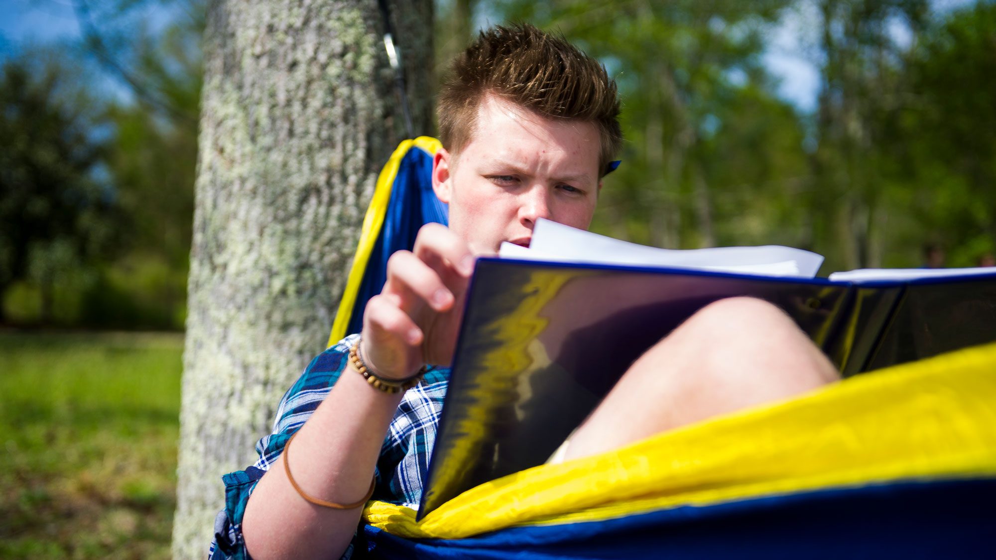 Student sitting in hammock reading notes