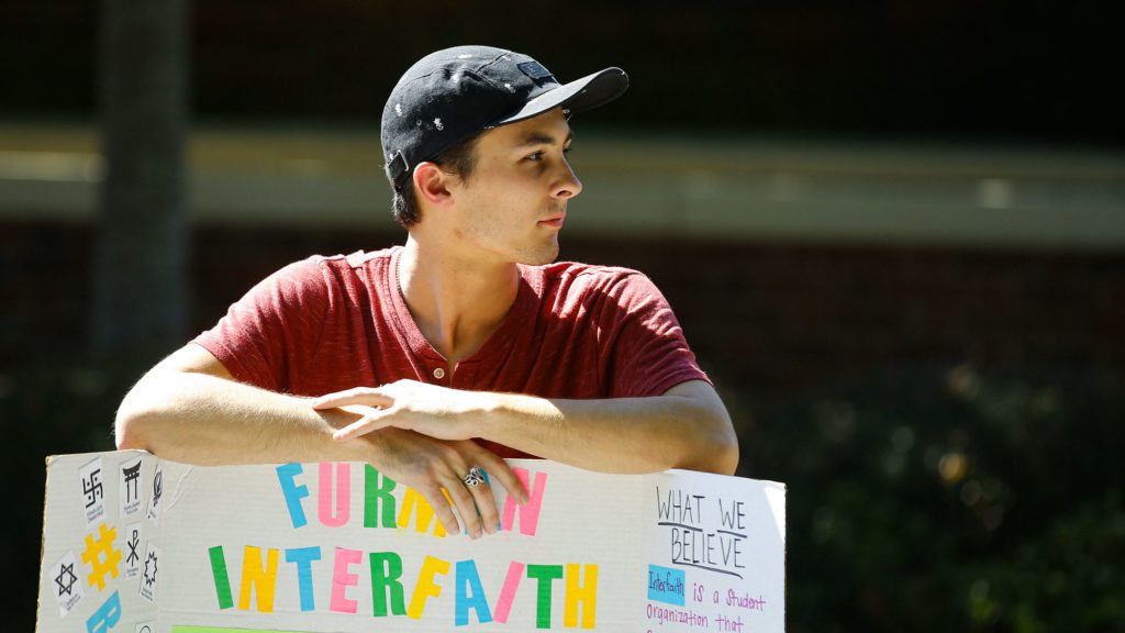 Student standing with interfaith sign