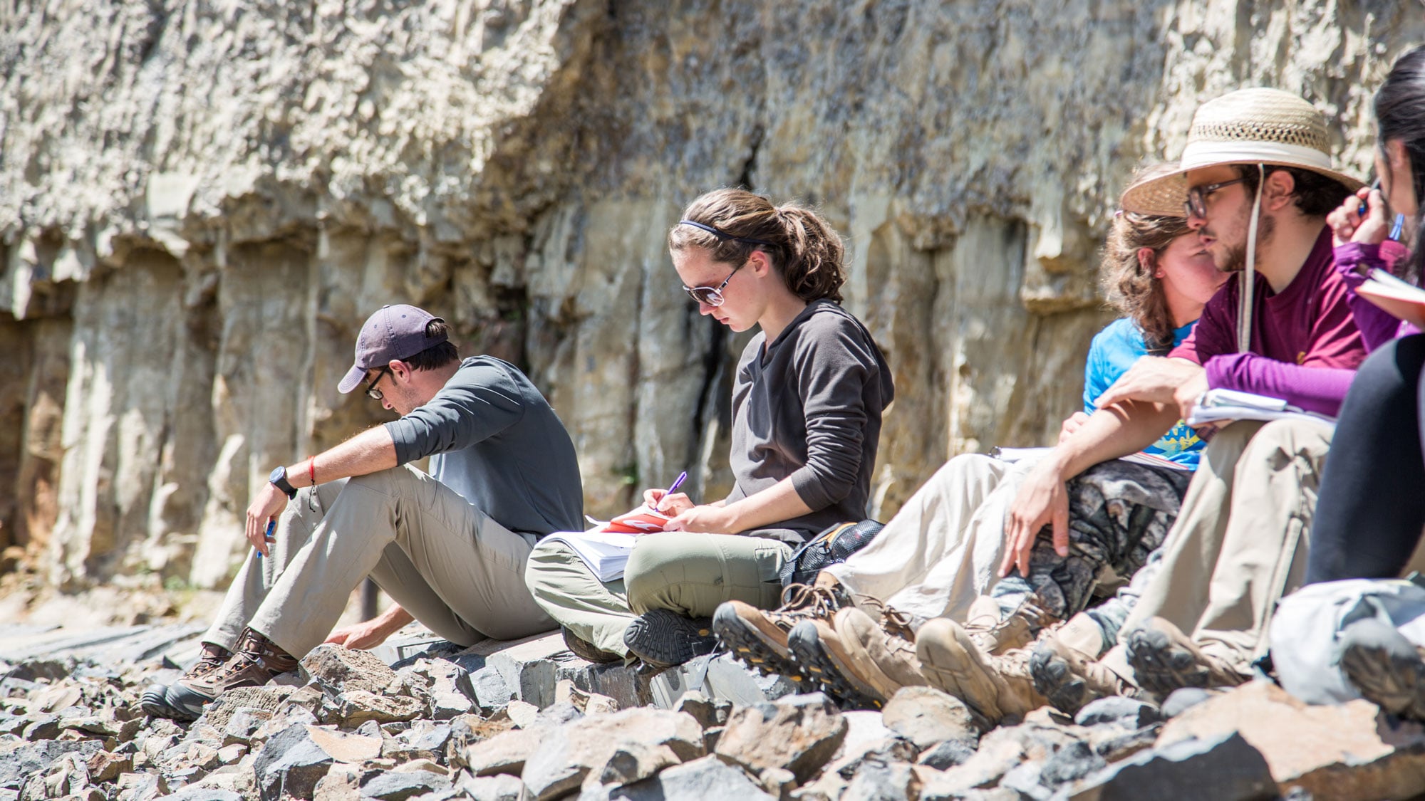 Students sitting on stone in the Rocky Mountains, attending a Study Away program