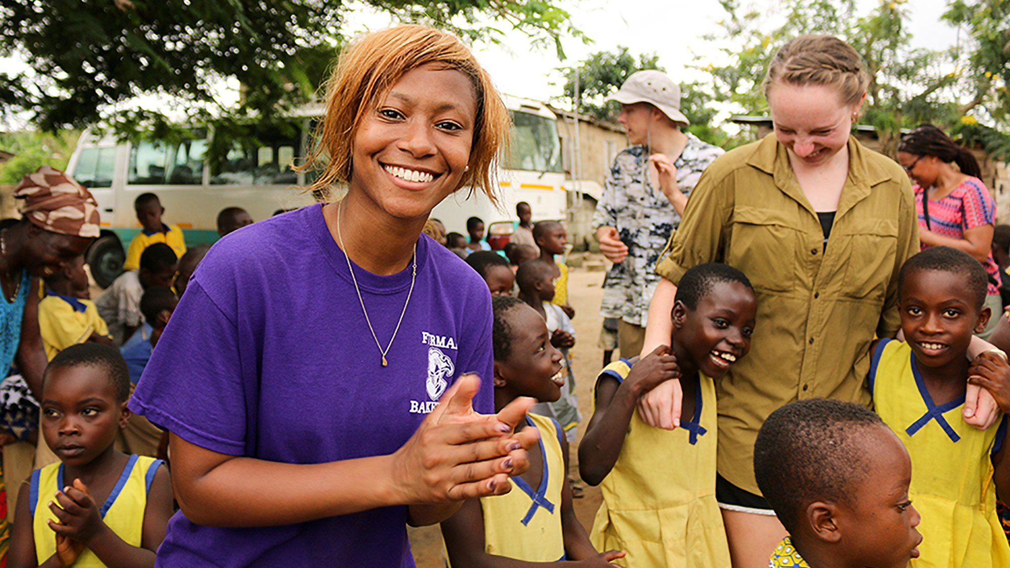 Student smiling, pictured among schoolchildren as part of the study away program to Ghana
