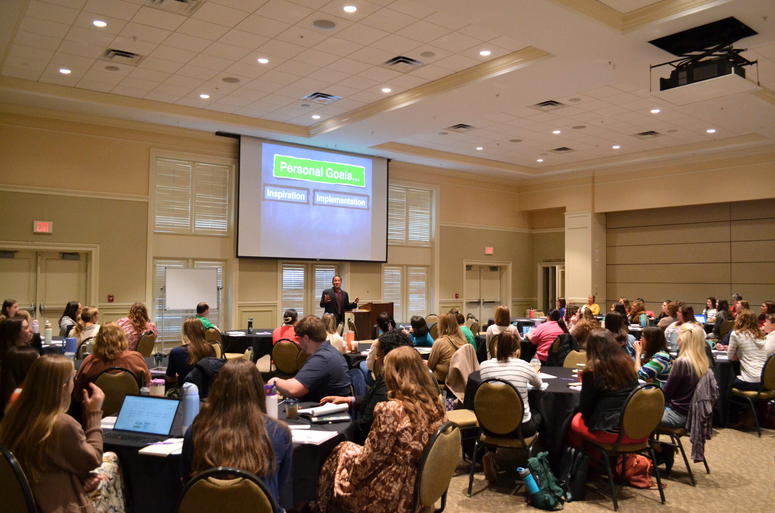 A consortium session featuring Alex Kajitani in a full room of teachers interacting with each other.
