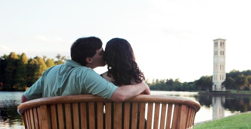 couple kissing on a bench by Furman University belltower